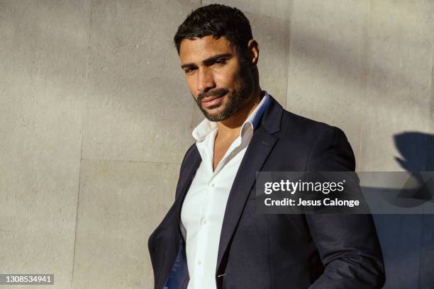 latin man, in suit. looking at the camera, smiling. with a wall of the street in the background. latins, businessman, unemployment, future, workers, and entrepreneurs concept. - editorial style stock pictures, royalty-free photos & images