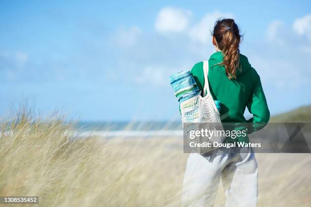 woman with plastic free reusable bag looking out to sea from beach. - jogging pants 個照片及圖片檔