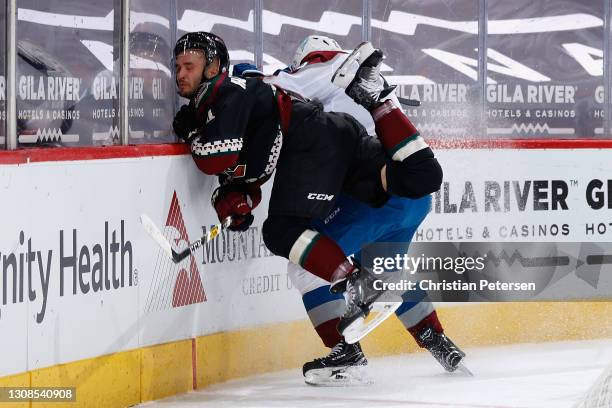 Niklas Hjalmarsson of the Arizona Coyotes crashes into the boards as he attempts to play the puck during the second period of the NHL game against...