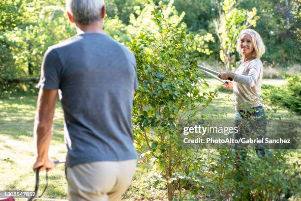 happy mature couple mowing lawn and cutting plants in backyard - grass cut out stock pictures, royalty-free photos & images