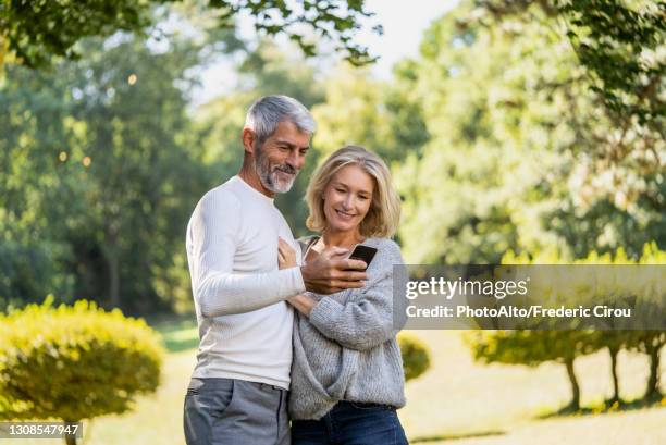 smiling mature couple using smartphone in backyard - 50 59 years stock pictures, royalty-free photos & images