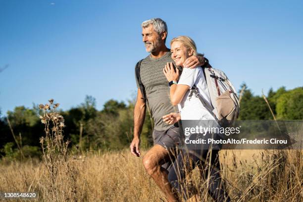 smiling mature couple hiking in forest - homem 55 anos imagens e fotografias de stock