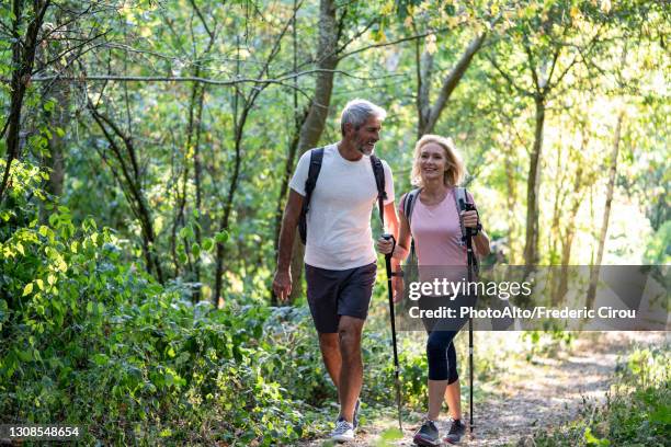 smiling mature couple hiking together in forest - hiking pole stock pictures, royalty-free photos & images