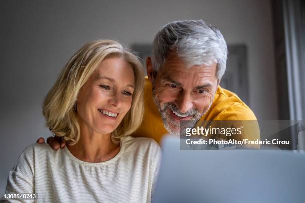 smiling mature couple using laptop - couple 50 55 laptop stock-fotos und bilder