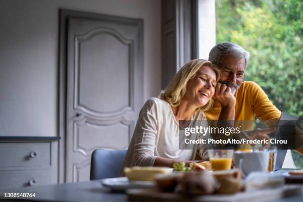 smiling mature couple using laptop at home - couple 50 55 laptop stock-fotos und bilder