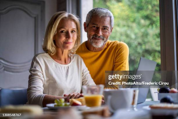 portrait of smiling mature couple using laptop at home - couple 50 55 laptop stock-fotos und bilder