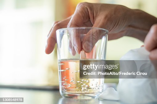 Close-up of woman's hand holding pill in glass of water Close-up of woman's hand holding pill in glass of water