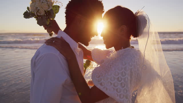 African american couple in love getting married, looking at each other on the beach at sunset