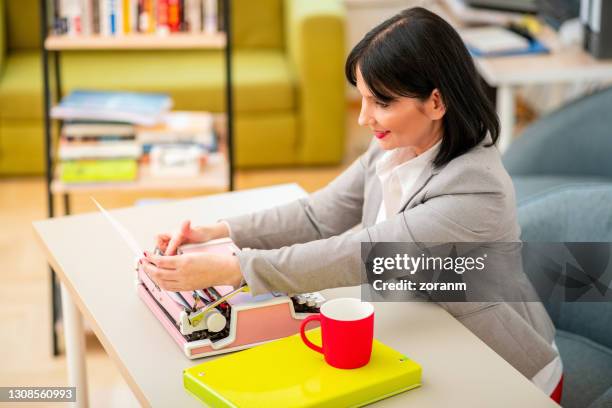 woman adjusting paper in typewriter for typing - copy editor stock pictures, royalty-free photos & images