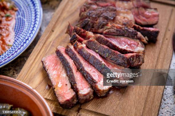 juicy medium rare beef steak cut on wooden board, seasoned with herbs - rib eye steak stock pictures, royalty-free photos & images