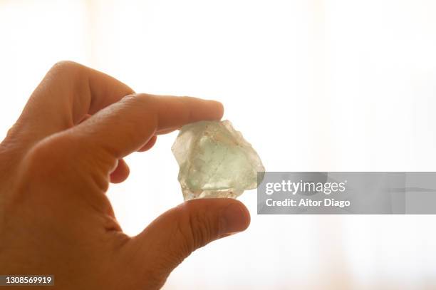 a man holds a mineral stone of fluorite in his hand - fluor stockfoto's en -beelden