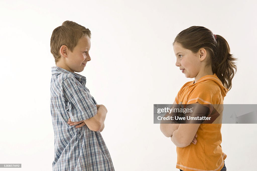 Boy and girl standing opposite each other with folded arms