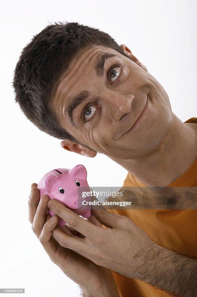 Smiling man holding a piggybank up to his ear