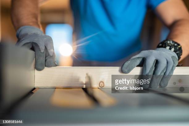 close-up of males hands using circular saw at construction site - glove stock pictures, royalty-free photos & images
