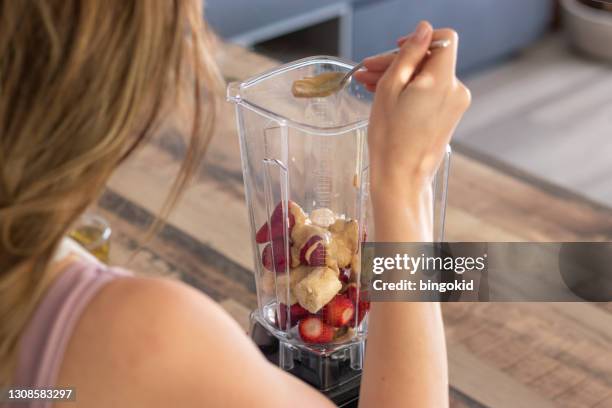 woman putting peanut butter in smoothie - peanut butter stock pictures, royalty-free photos & images