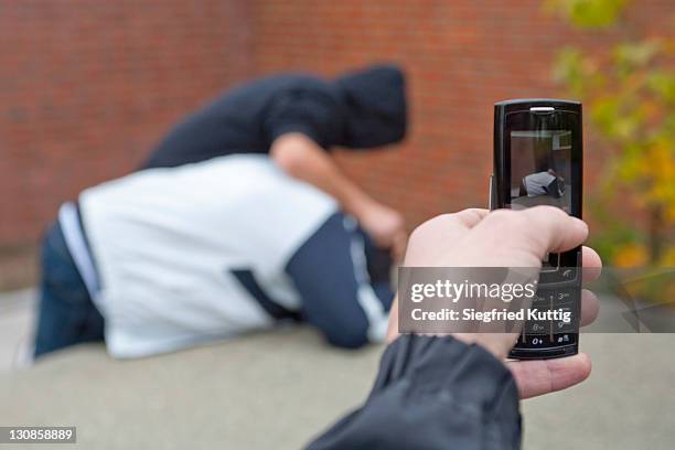 boy pushing another boy down onto a table tennis table being filmed with a mobile phone - teen doing filming imagens e fotografias de stock