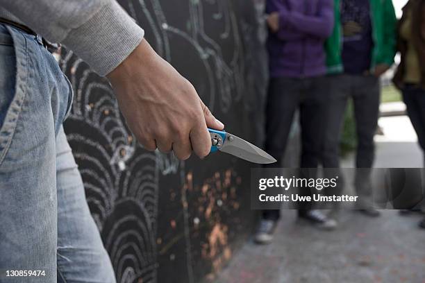 adolescent threatening a group with a knife - agressão imagens e fotografias de stock