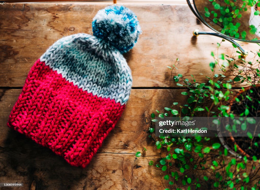 A hand knitted woollen hat on a table - stock photo