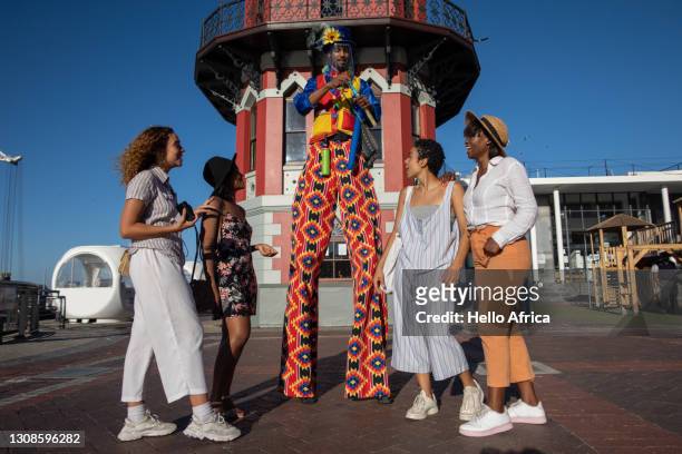 four young woman, getting ballons blown by an entertainer at the cape town waterfront. - 2021 a funny thing stock pictures, royalty-free photos & images