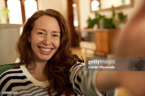 smiling young woman taking a selfie at home - photographing interior stock pictures, royalty-free photos & images