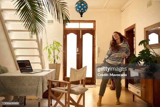 smiling young woman dancing around her living room at home - expressive and music stock pictures, royalty-free photos & images