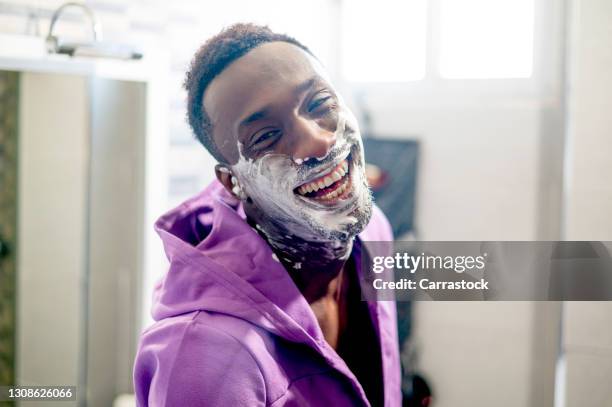 smiling african man with shaving foam on his face - male hair removal stockfoto's en -beelden