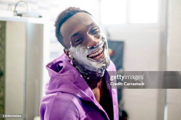 smiling african man with shaving foam on his face - man shaving foam stock pictures, royalty-free photos & images