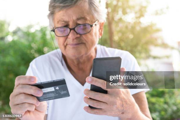 senior woman with credit card - debit card fraud stock pictures, royalty-free photos & images