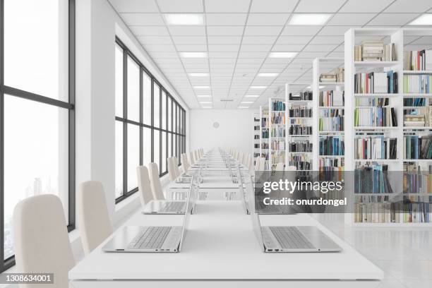 moderne bibliothek mit laptops auf dem tisch und büchern auf den bücherregalen. - überbelichtet stock-fotos und bilder