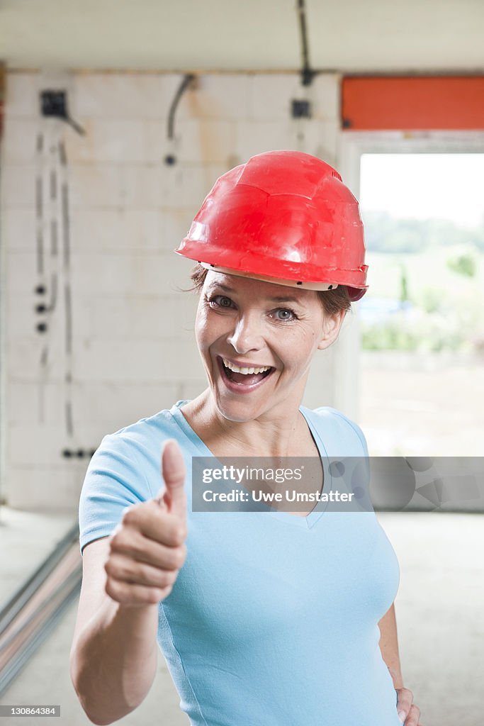 Craftswoman with hard hat giving a thumbs up
