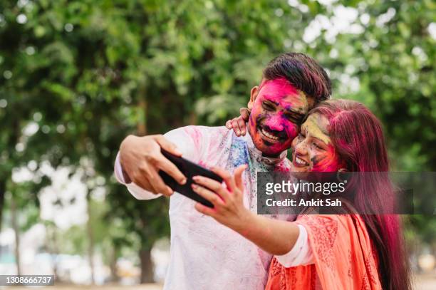 young couple taking selfie using mobile phone - holi festival and indian person stock pictures, royalty-free photos & images