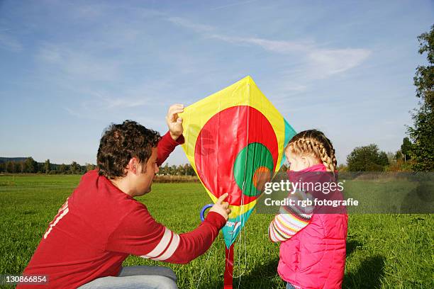 father and his three-year-old daughter playing with a kite - 2 year old blonde girl father stock-fotos und bilder