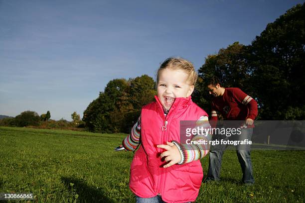 father and his three-year-old daughter playing with a kite - 2 year old blonde girl father stock-fotos und bilder