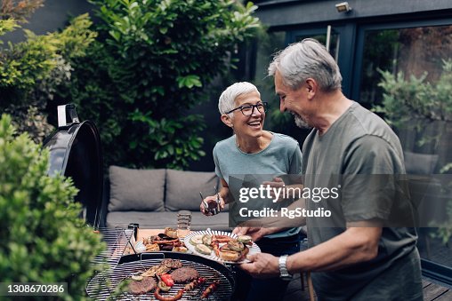 Hoger paar dat vlees grillt en geniet in de achtertuin Hoger paar dat vlees grillt en geniet in de achtertuin