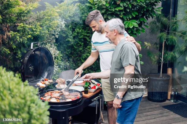 mann und sein vater machen grillen und genießen im hinterhof - bbq father stock-fotos und bilder