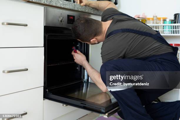 jonge mens die oven in keuken herstelt - kitchen straighten stockfoto's en -beelden