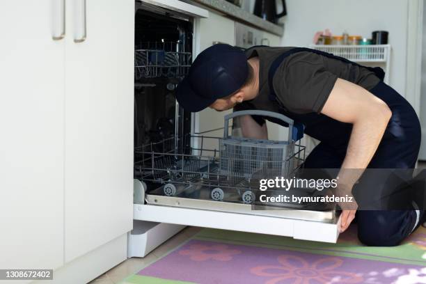 worker repairing the dishwasher in the kitchen - máquina de lavar louça imagens e fotografias de stock