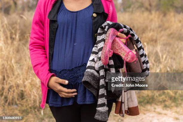 An asylum seeker from Honduras, traveling with her three children while 8 months pregnant, pauses after crossing the Rio Grande from Mexico on March...