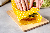 Woman hands wrapping a healthy sandwich in beeswax food wrap and cotton bag