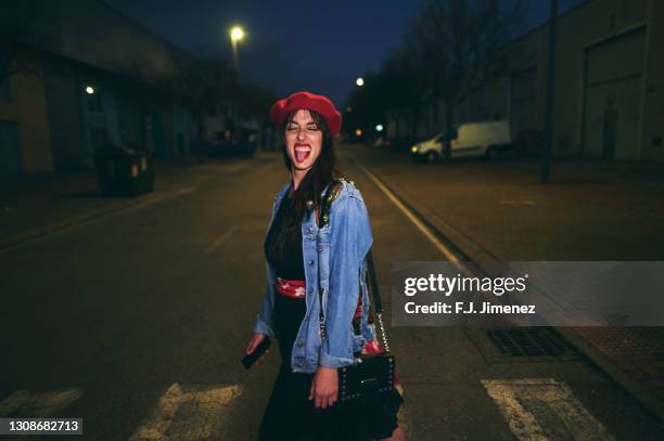 woman walking on the street at night sticking out her tongue - flash stockfoto's en -beelden