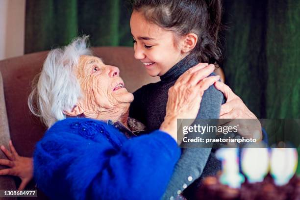 great-grandmother is hugging her great-granddaughter at her 100th birthday - 100 birthday stock pictures, royalty-free photos & images