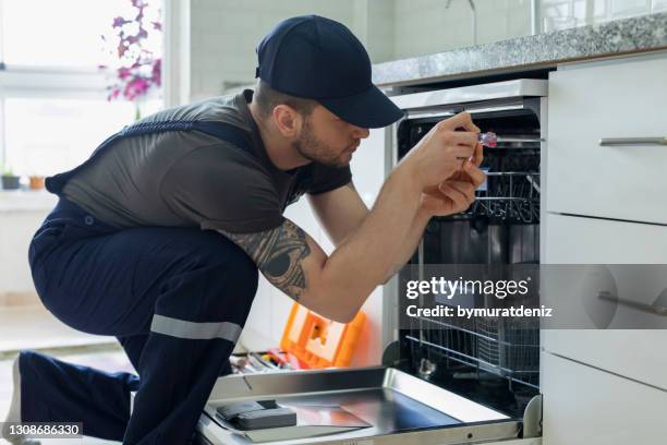 techniker untersucht spülmaschine - haushaltsmaschine stock-fotos und bilder