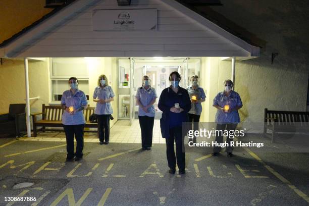 Nursing staff at the Langholme Care Home stand together and hold candles at 8pm to mark a year since the beginning of the Coronavirus pandemic on...
