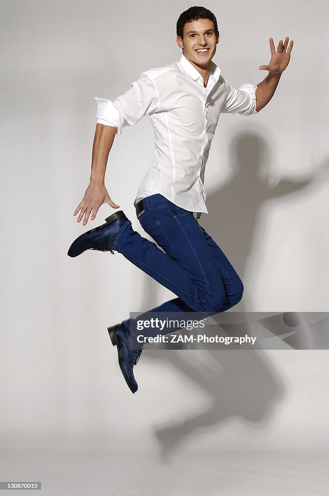 Young man in white shirt and blue jeans jumping