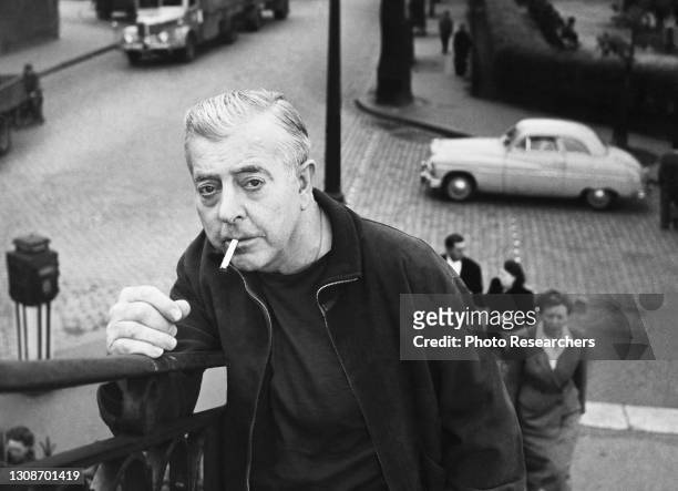 Portrait of French poet and screenwriter Jacques Prevert as he smokes a cigarette on the Pont Levant de la Rue de Crimee, Paris, France, circa 1955.