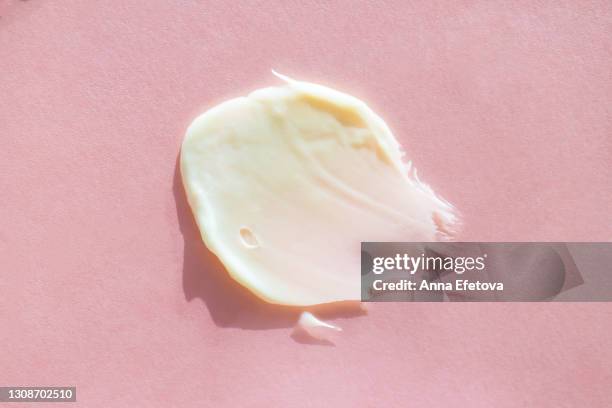 smear of pastel beige body cream on light pink background. concept of natural skin care cosmetic. extreme close-up and flat lay style - fumigation photos et images de collection