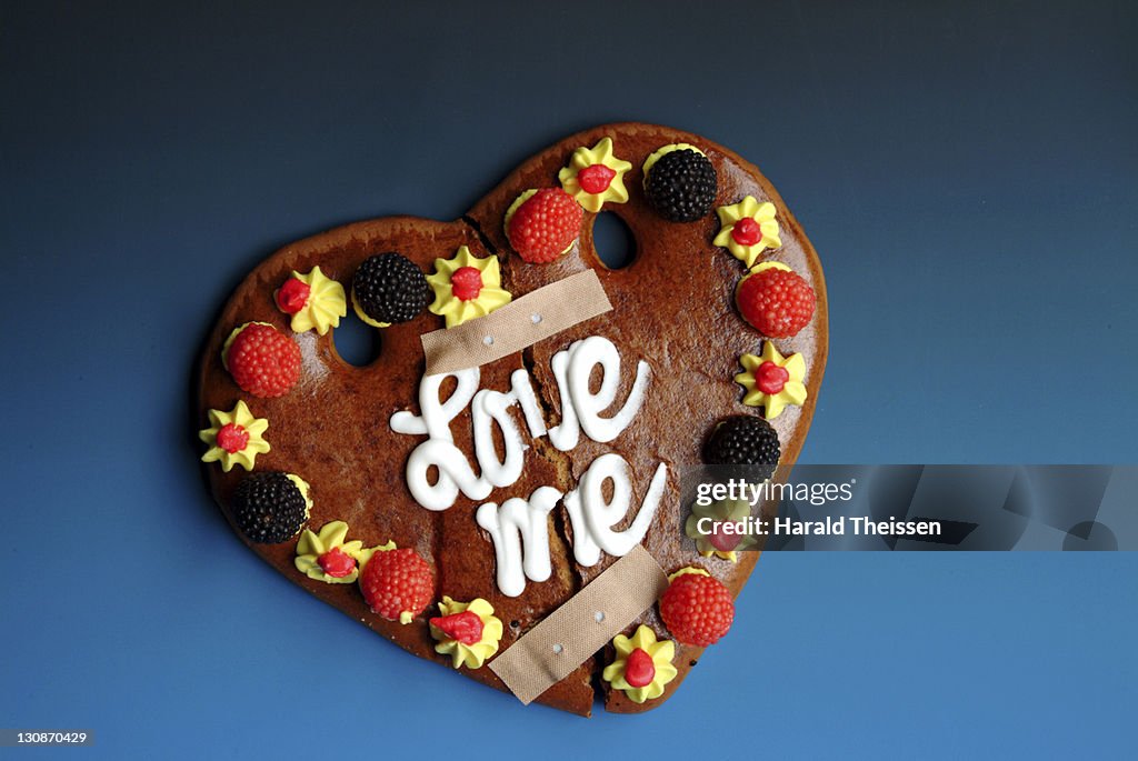 Broken love heart made of honey cake repaired with band aids