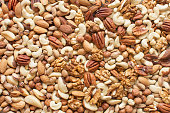 Assorted nuts: hazelnuts, walnuts, brazilian nuts, pecans, pistachio, almonds, cashews Flatlay organic mixed nuts background. Healthy food, useful microelements and vitamins. Useful health snack.