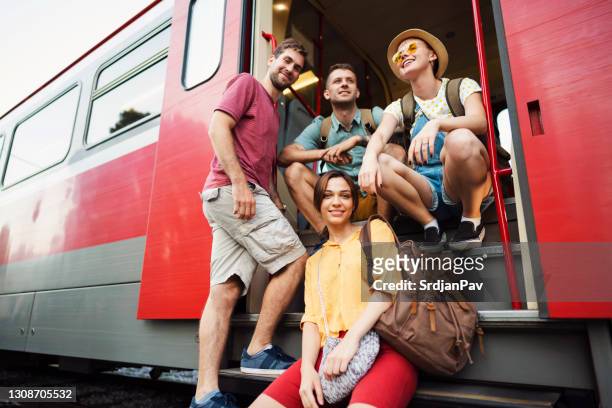 vista ad angolo basso di un gruppo di amici all'uscita del treno in posa per la foto - viaggio treno foto e immagini stock