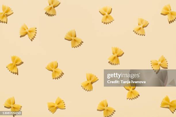 pattern made of uncooked pasta on beige background with shadows. top view, flat lay - flat pasta stock-fotos und bilder